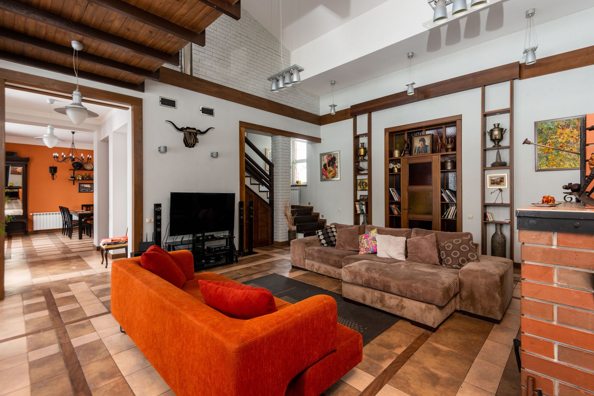 Interior of contemporary spacious living room with sofas and TV set placed near wall with decorative elements in modern flat